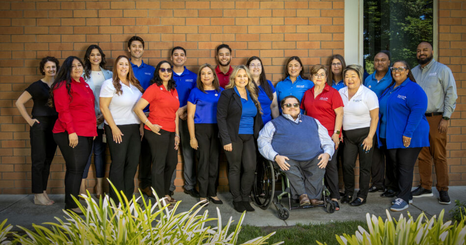 Employees from Health Plan of San Joaquin posing in front of a brick building.