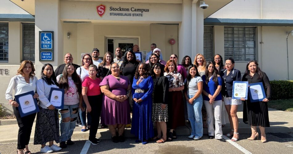 A group of scholarship recipients posing in front of the Stanislaus State Stockton Campus.