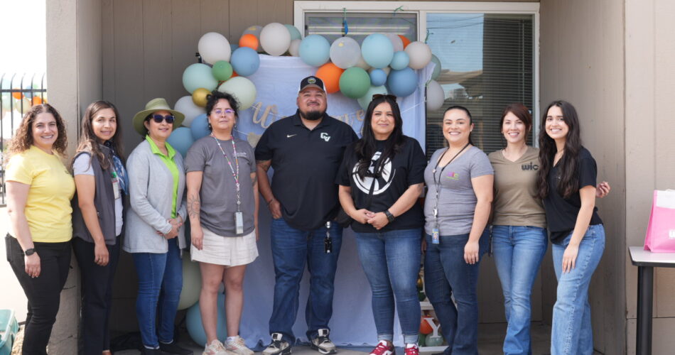 Members of the community posing in front of a balloon backdrop for a Health Plan event.