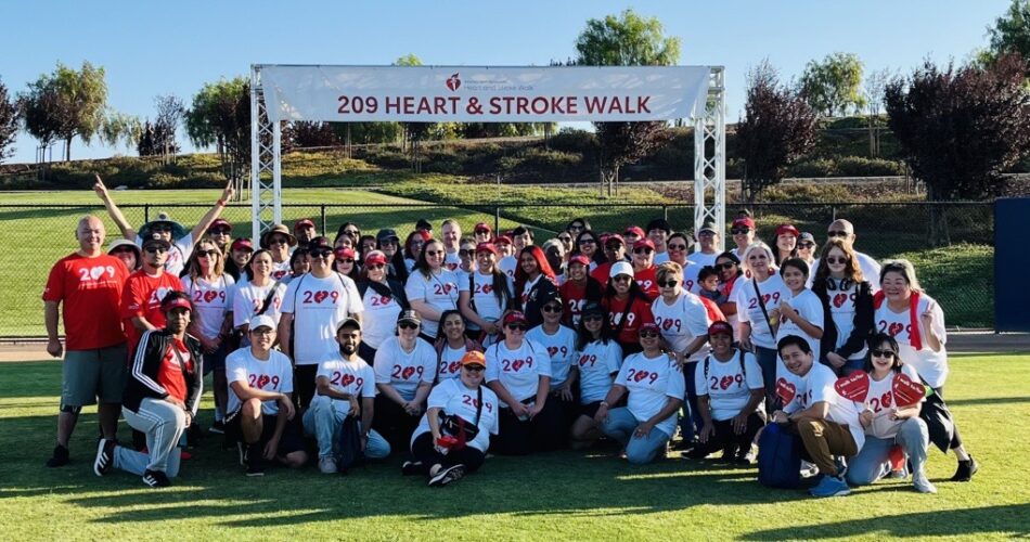 A group of participants standing in front of the banner for the 209 Heart and Stroke Walk.