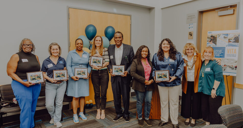 Men and women holding plaques for the Volunteer Income Tax Assistance (VITA) program.