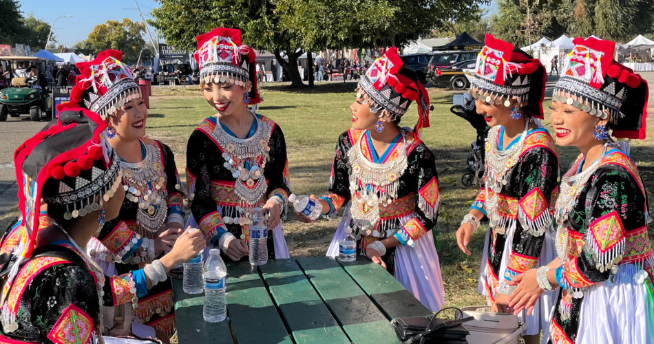 A group of women in their heritage clothing standing around a table.