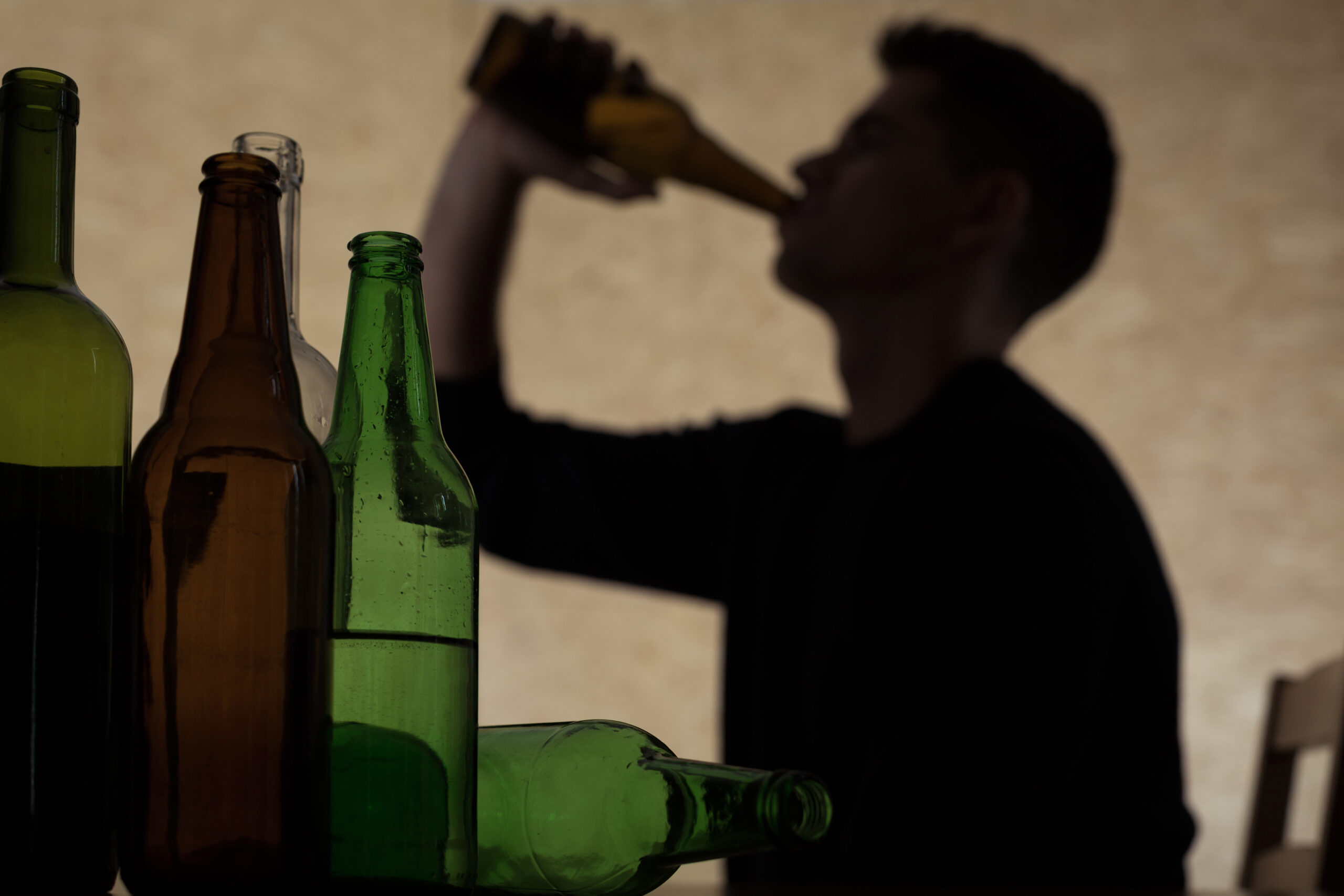 Teenager drinking beer A man drinking alcohol. There are several empty bottles indicating a drinking problem.