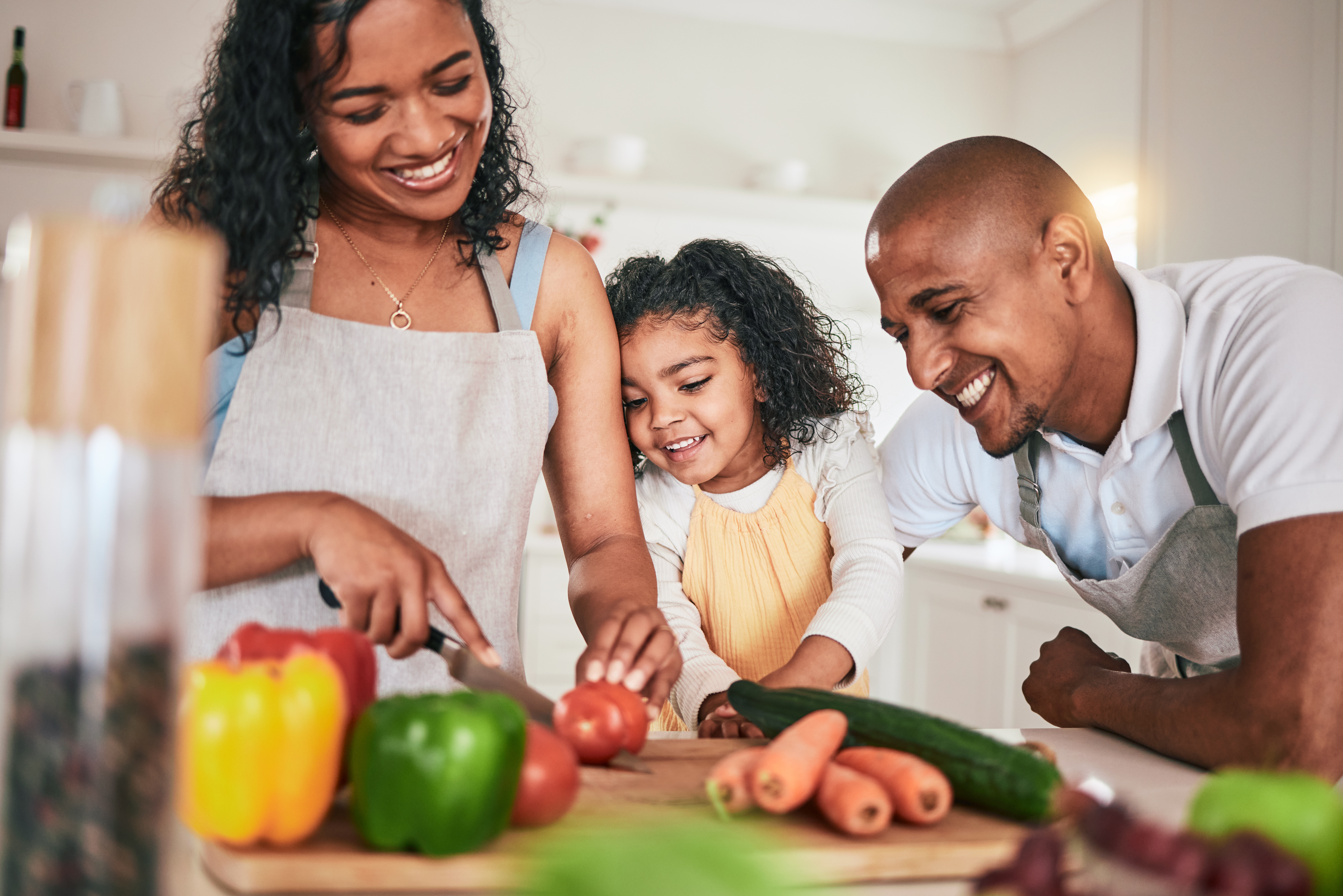 Family, cutting and cooking vegetables together. Learning chef skill with parents and child in kitchen. Nutrition, healthy food and organic with people teaching and learn to cook at home with bonding