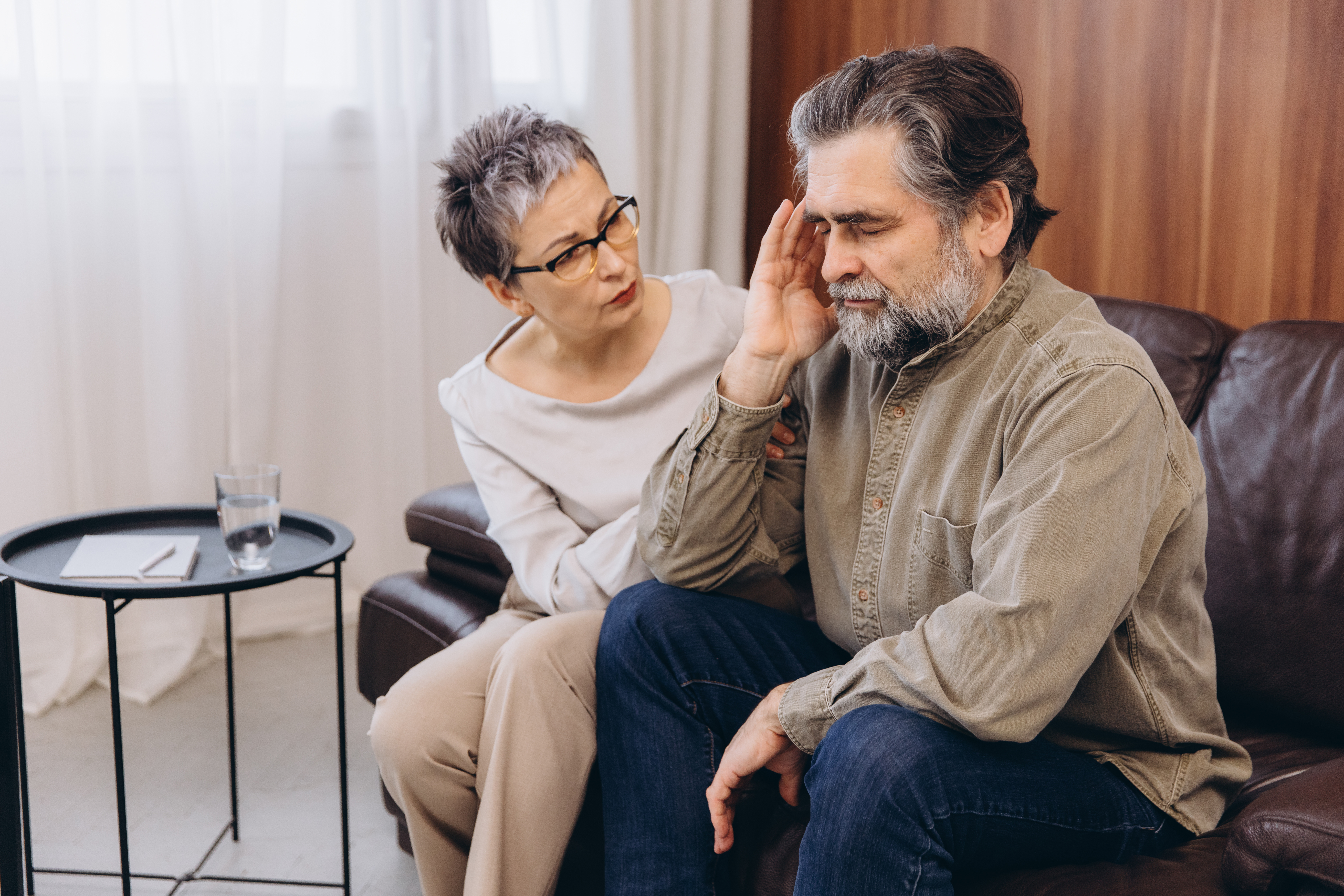 Psychologist counseling older man dealing with stress or headache